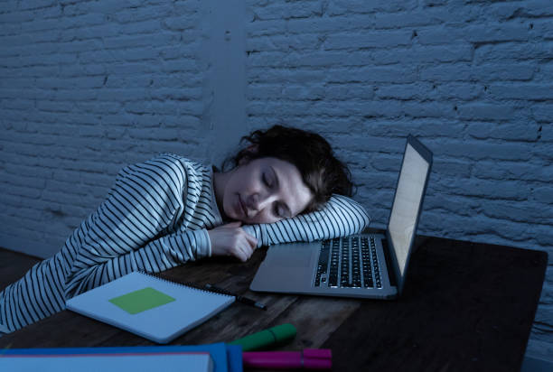 istock Overworked and tired female student asleep on the desk while working late at night on her laptop. Feeling fatigued and sleepy resting on her desk. In a studying for exams or overwork concept. 1163756049