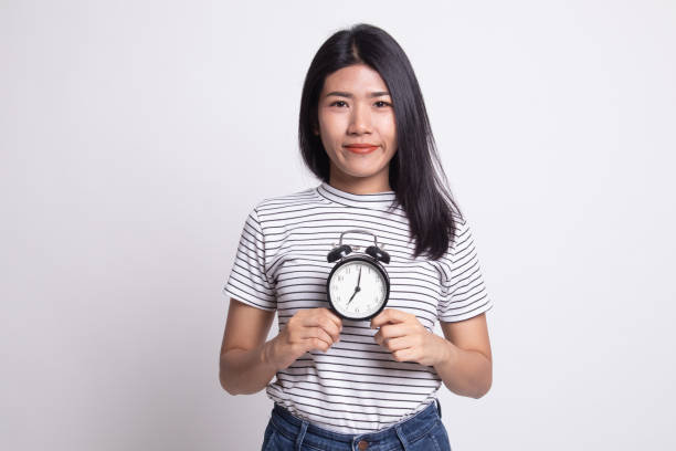 istock Young Asian woman smile with a clock. 1163756345