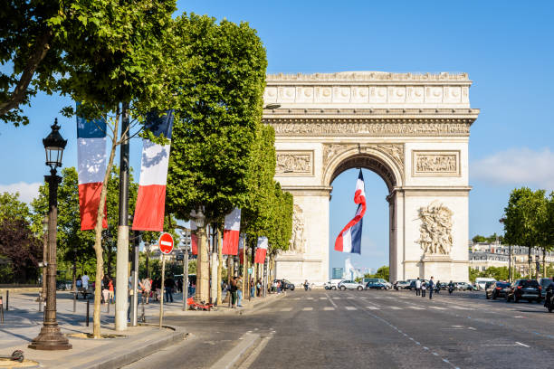 una grande bandiera francese sventola sotto l'arco di trionfo a parigi, in francia. - arc arc de triomphe paris france street foto e immagini stock