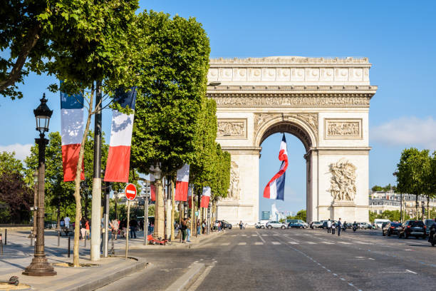 A large french flag flies under the Arc de Triomphe in Paris, France. Paris, France - July 15, 2019: To mark the Bastille Day a large french flag flies under the vault of the Arc de Triomphe and the avenue des Champs-Elysees is decked with french flags. bastille day photos stock pictures, royalty-free photos & images