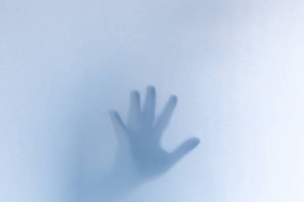 istock Defocused scary ghost hands behind a white glass background 1163761253