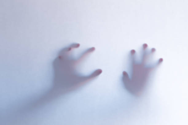 istock Defocused scary ghost hands behind a white glass background 1163761280