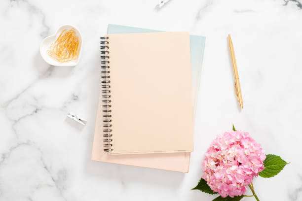 istock Blank paper notebook, pink hydrangea flower and golden stationery on marble background. Flat lay, top view modern home office desk. Fashion blogger workspace concept. 1163764101