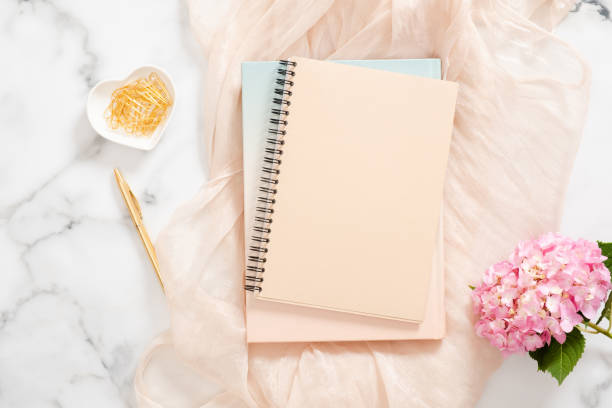 istock Top view home office desk table with blank paper notebook, pink hydrangea flower, pastel blanket and stylish accessories on marble background. Feminine background, fashion blogger workspace concept 1163764117
