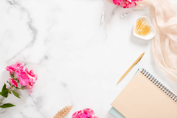 istock Flatlay home office desk table. Workspace with pale pastel beige notebook, pink flowers and decorations on white background. Flat lay, top view. 1163764121