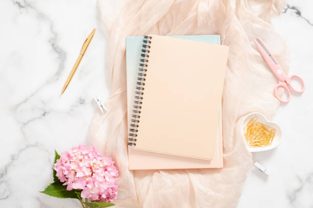 istock Modern home office desk workspace with pink hydrangea flower, pastel blanket, blank paper notepad, golden stationery and feminine accessories on marble background. Fashion blogger workplace concept. 1163764122