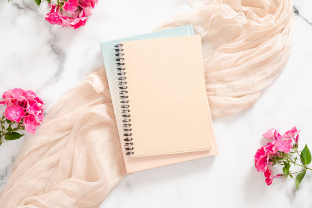 istock Composition with blank paper notebook, pink flowers and pastel blanket on marble background. Flat lay, top view still life concept. 1163764131