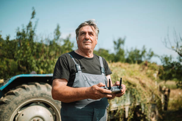 Mature farmer flying a drone over a field