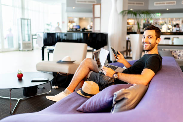 Man using laptop and smartphone, working from the hotel lobby