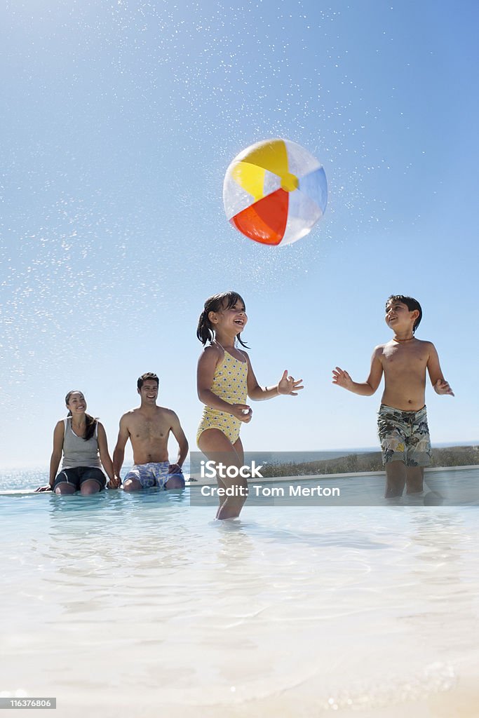 Parents en regardant les enfants jouer avec le ballon dans la piscine - Photo de Piscine libre de droits