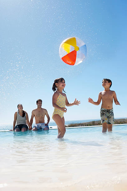 parents en regardant les enfants jouer avec le ballon dans la piscine - beach ball swimming pool ball child photos et images de collection