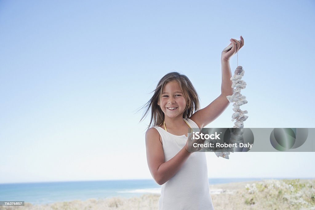 Girl holding carcasa necklace en la playa - Foto de stock de Collar libre de derechos