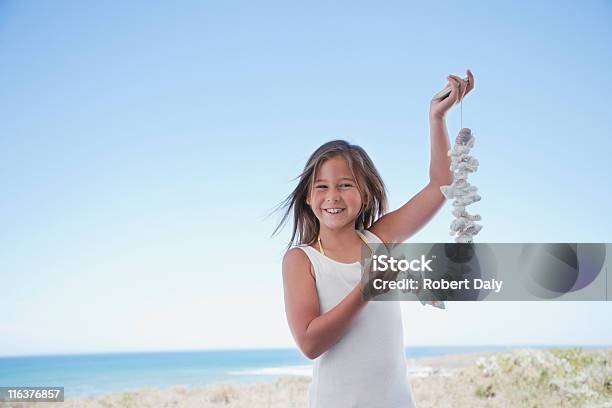 Girl Holding Carcasa Necklace En La Playa Foto de stock y más banco de imágenes de Collar - Collar, Concha de mar, Concha - Parte del cuerpo animal