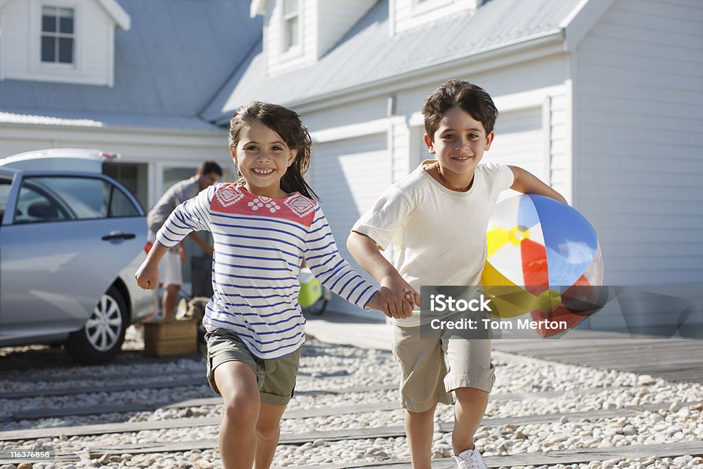 Frère et Soeur avec ballon de plage de course sur l'allée principale - Photo de Voiture libre de droits