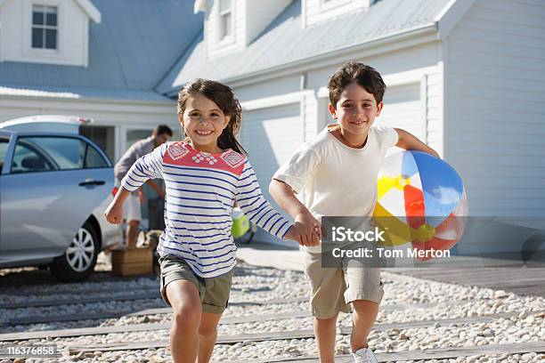 Photo libre de droit de Frère Et Soeur Avec Ballon De Plage De Course Sur Lallée Principale banque d'images et plus d'images libres de droit de Voiture