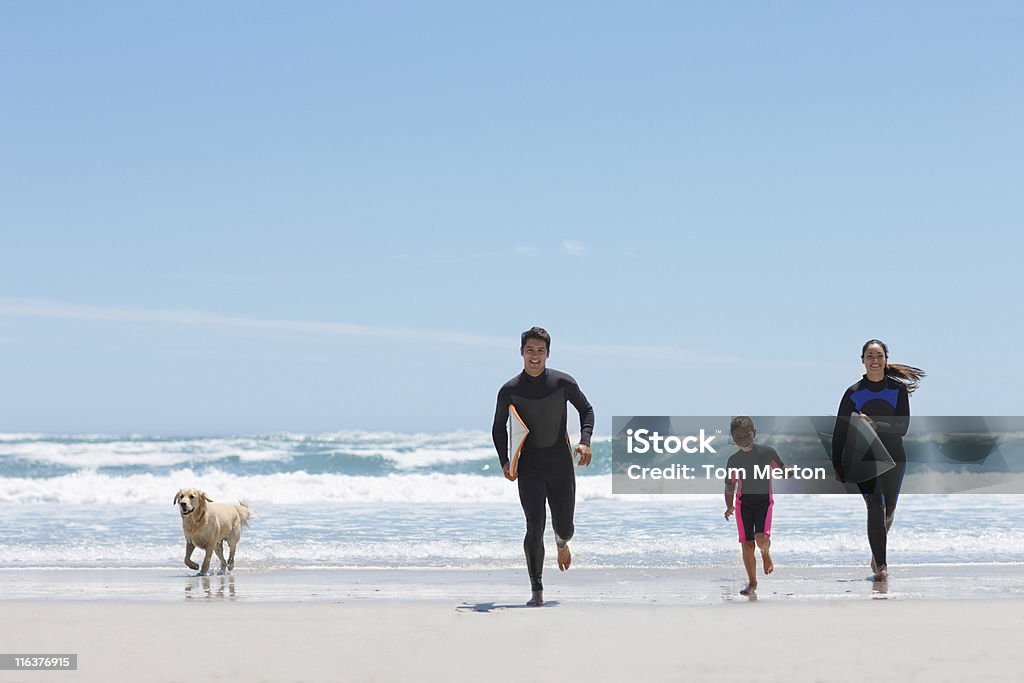 Famille avec des planches de surf sur la plage de jogging - Photo de Famille libre de droits