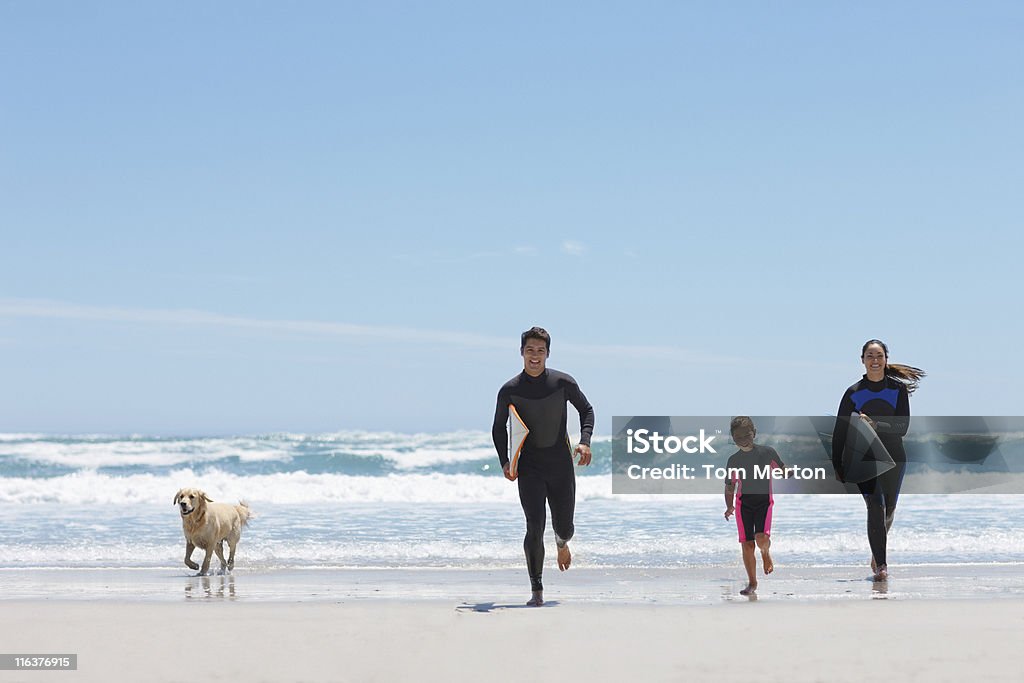 Famiglia con tavole da surf in esecuzione sulla spiaggia - Foto stock royalty-free di Famiglia