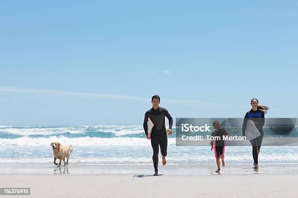 Famiglia Con Tavole Da Surf In Esecuzione Sulla Spiaggia - Fotografie stock e altre immagini di Famiglia
