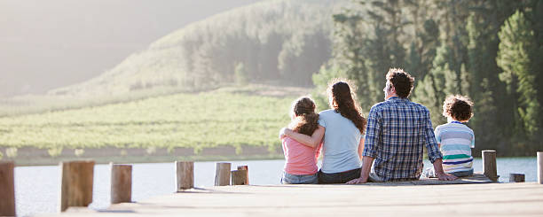 Family sitting on dock by lake  serene people photos stock pictures, royalty-free photos & images