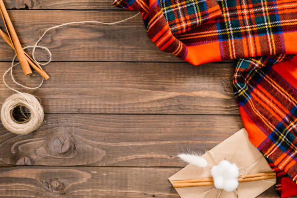 istock Flatlay autumn composition. Frame of red plaid, cinnamon sticks, rope, envelope on wooden background. Flat lay, top view, copy space. Cozy home desk, hygge, autumn fall concept 1163770178