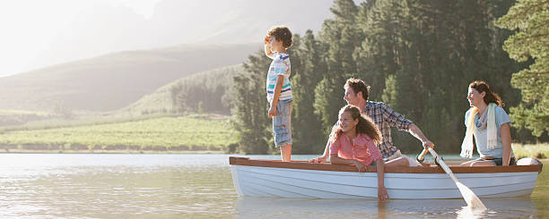 famille en bateau à rames sur le lac - people in a row in a row human face smiling photos et images de collection