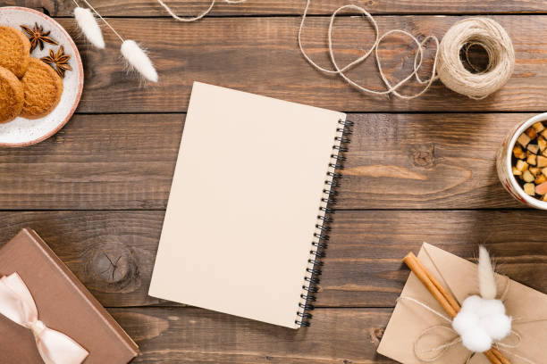 istock Workspace with craft paper notepad, rope, cup of tea, cookies, gift box, vintage envelope. Stylish home office desk. Autumn or Winter concept. Flat lay, top view 1163770191