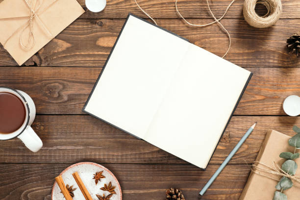 istock Flatlay composition with blank book, cup of tea, craft envelope, pen, gift box, cinnamon sticks, present on wooden background. Cozy autumn or winter holiday concept. Flat lay, top view, copy space 1163770643