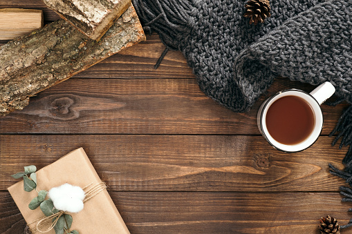 Autumn composition. Cup of tea, women fashion scarf, gift box, firewood on wooden background. Flat lay, top view, copy space. Scandinavian hygge concept.