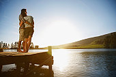 Couple on dock hugging and watching sun set over lake