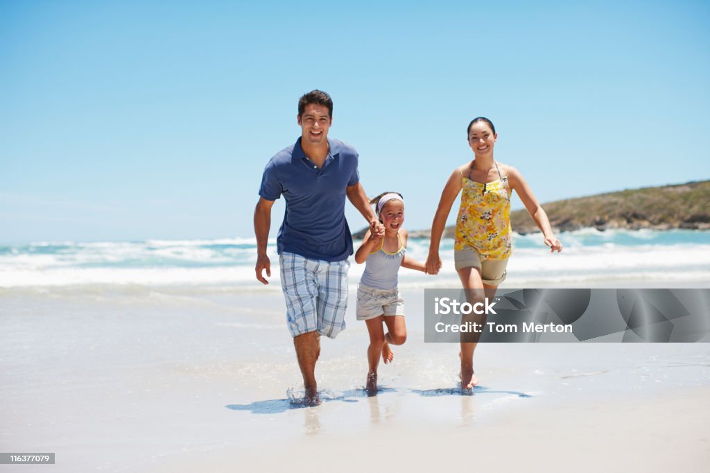 Family running on beach  Family Stock Photo