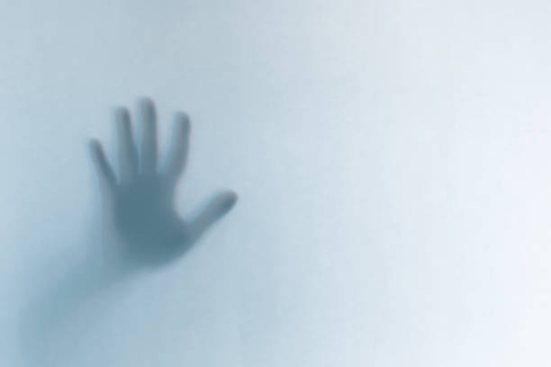 istock Defocused scary ghost hands behind a white glass background 1163770815