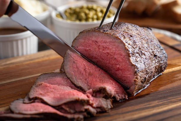 slicing eye of round roasted beef with knife - roast beef fotos imagens e fotografias de stock