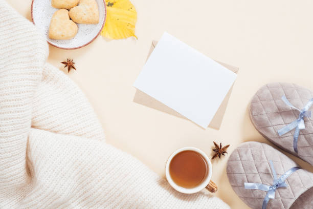istock Autumn flatlay composition. Feminine desktop with white knitted plaid, letter, gift box, slippers, tea cup, fallen leaves on pastel beige background. Flat lay, top view. Autumn, fall concept. 1163771696