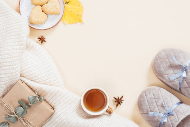 istock Autumn flatlay composition. Feminine desktop with white knitted plaid, gift box, slippers, tea cup, fallen leaves on pastel beige background. Flat lay, top view. Autumn, fall concept. 1163771739
