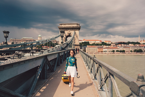 Young woman with umbrella and suitcase just arriving in Budapest