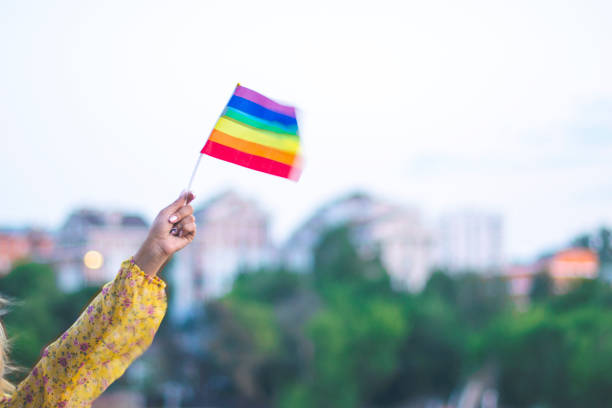 Girl's hand in dress holding multi-colored LGBT flag stock photo