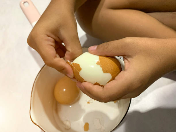 istock Little Asian boy is peeling boiled egg 1163772259