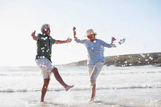 pareja senior jugando en el mar - senior adult happiness lifestyles cheerful fotografías e imágenes de stock