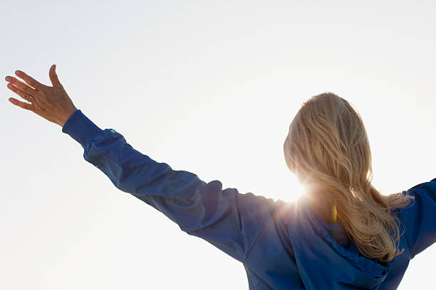 sol brillante detrás de mujer con los brazos estirados - arms raised arms outstretched sky human arm fotografías e imágenes de stock