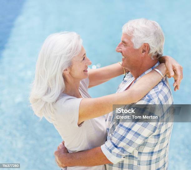 Photo libre de droit de Couple Senior Embrassant Au Bord De La Piscine banque d'images et plus d'images libres de droit de Troisième âge - Troisième âge, 60-64 ans, 65-69 ans