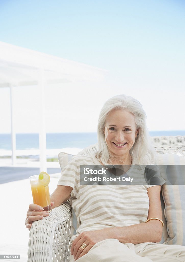 Senior donna bere cocktail sulla terrazza - Foto stock royalty-free di Donne