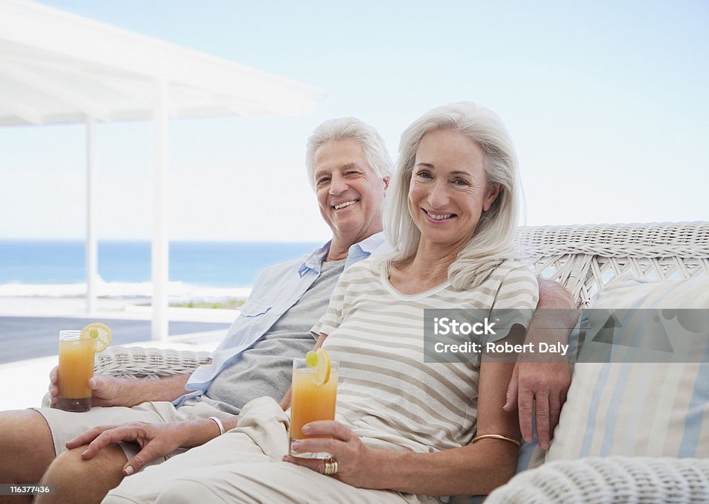 Starsza para picia koktajli na plaży patio - Zbiór zdjęć royalty-free (Baby boomer)