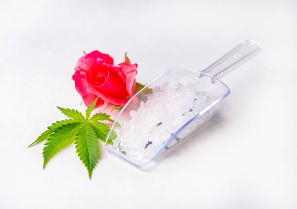 Cannabis infused bath salts with marijuana leaf and rose bud isolated over white background
