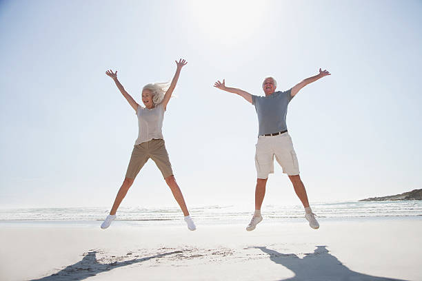 Senior couple jumping on beach  legs apart stock pictures, royalty-free photos & images