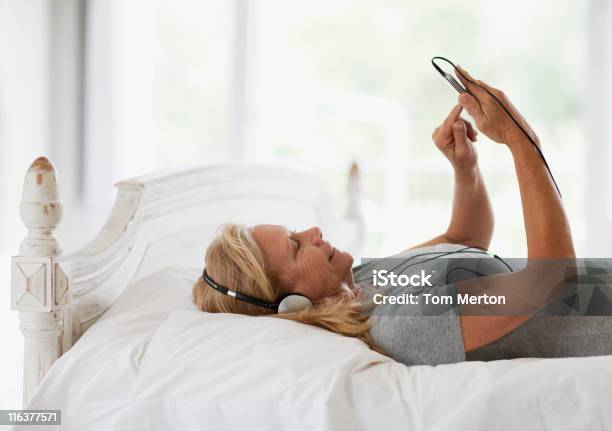 Donna Posa Sul Letto E Ascoltare Musica Sul Lettore Mp3 - Fotografie stock e altre immagini di Letto