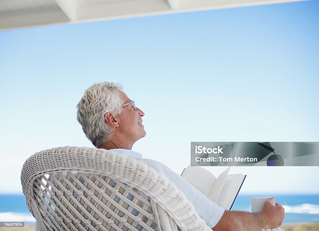 Homme âgé lisant un livre sur la plage Terrasse - Photo de Troisième âge libre de droits