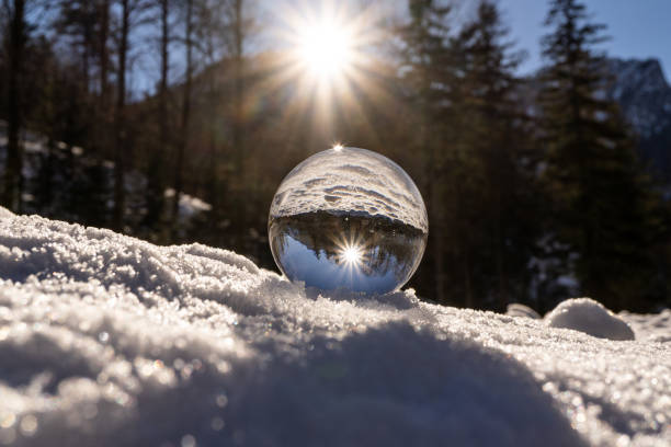 linsenkugel im winter in österreich europa, kristallkugel im schnee mit einem erstaunlichen sonnenuntergang im hintergrund - ice crystal winter nature ice stock-fotos und bilder