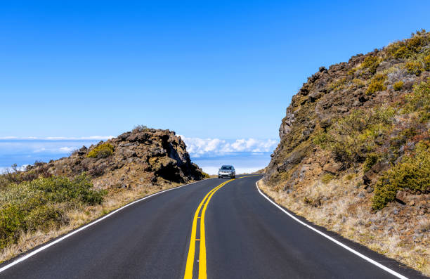 Winding Road - A mid-size SUV driving on a curvy and high elevation section of Haleakala Highway in Haleakala National Park on a bright sunny afternoon. Maui, Hawaii, USA. stock photo