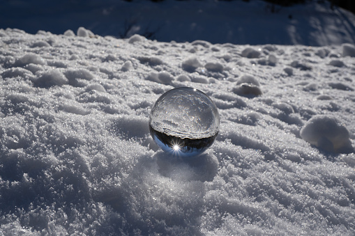 lens ball during winter in austria europa, crystal ball in the snow with an amazing sunset in the background