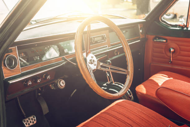 istock Classic retro or vintage car interior with steering wheel in sunset light, close up 1163778497